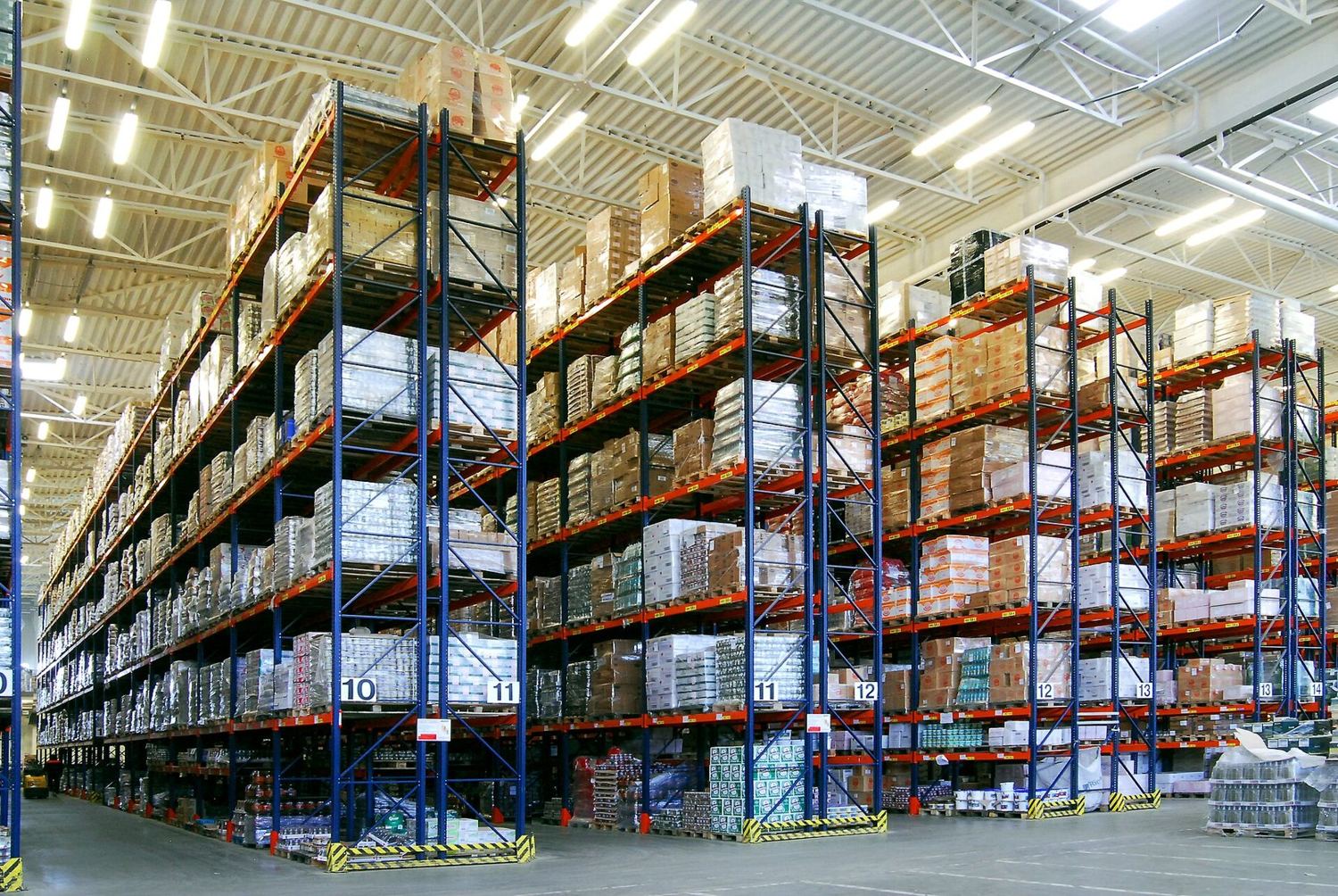 Fully loaded pallet racking down a lit aisle